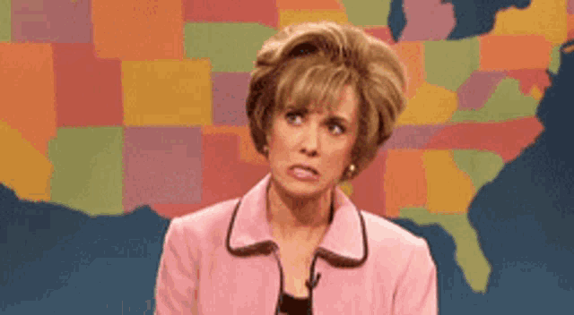a woman in a pink jacket is making a funny face in front of a map of the united states