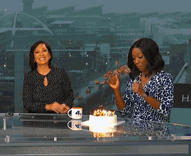 two women are sitting at a table with a cake and a mug that says 4 on it