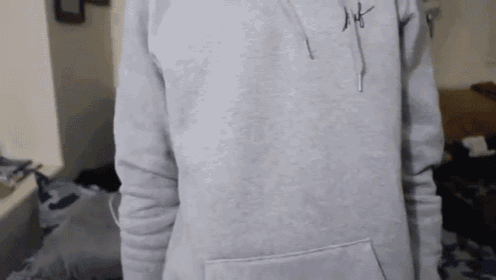 a person wearing a grey hoodie with a signature on the front .