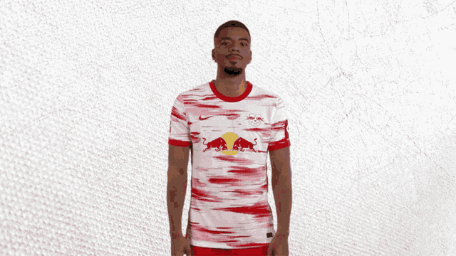 a man wearing a red bull shirt stands in front of a white background