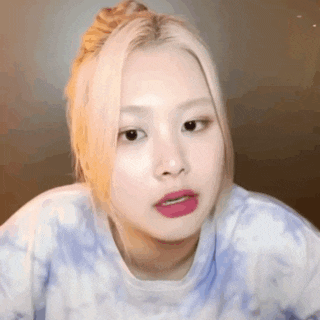 a woman with blonde hair and pink lipstick is wearing a tie dye shirt .