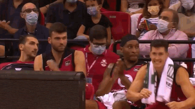a group of people wearing face masks are sitting in a stadium