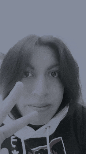 a black and white photo of a woman giving a peace sign with her fingers