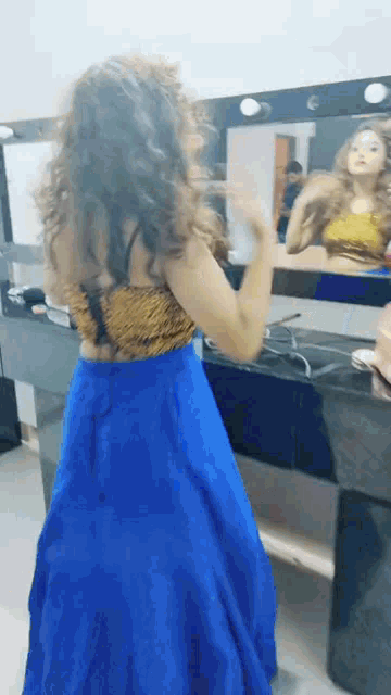 a woman is standing in front of a mirror wearing a blue skirt