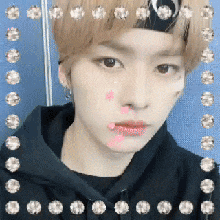 a young man wearing a headband and a black hoodie is taking a selfie .