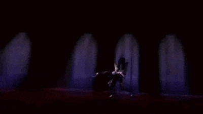 a man is kneeling down in a dark room holding a sword .