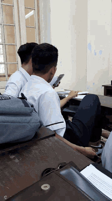 a man sitting in a classroom with a backpack that says ' abercrombie ' on it
