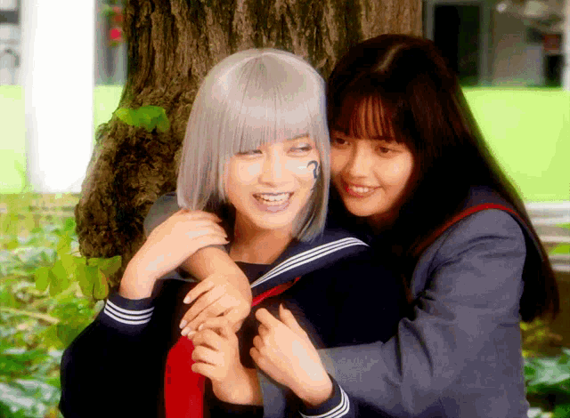 a girl with a tattoo on her arm is hugging a girl with gray hair