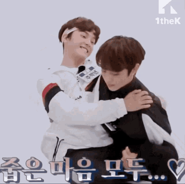 two young men are hugging each other with korean writing on the bottom right