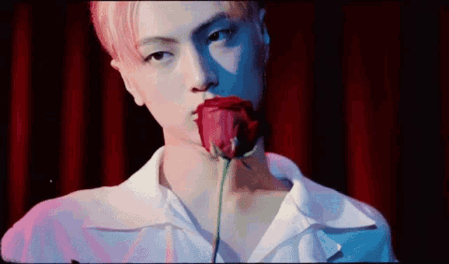 a man is holding a red rose in his mouth .