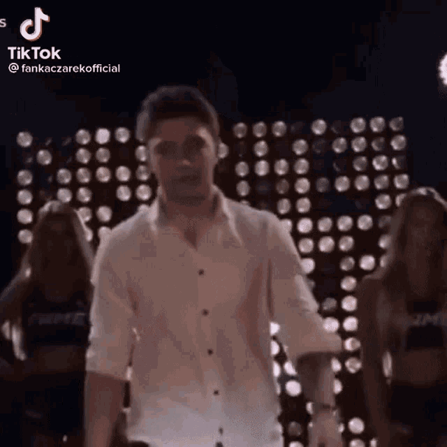 a man in a white shirt is dancing in front of a wall of lights ..