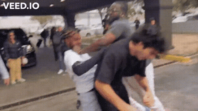 a group of people are fighting on a street with the words veed.io in the corner .