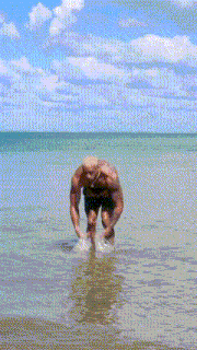a shirtless man is standing in the water wearing a pair of shorts that say hustle