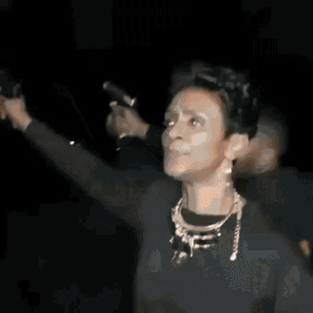 a woman is dancing with her arms in the air in a dark room .