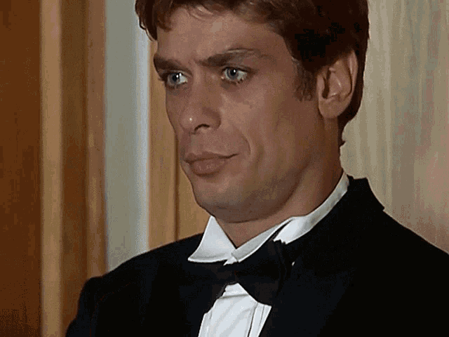 a man in a tuxedo with a bow tie looks to the side
