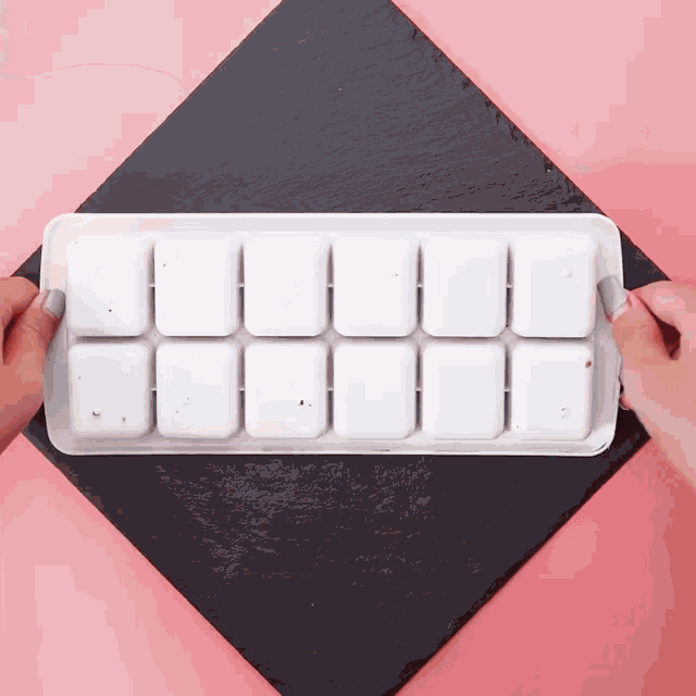 a person is holding a tray of ice cubes
