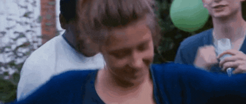 a woman in a blue sweater is dancing with a group of people .
