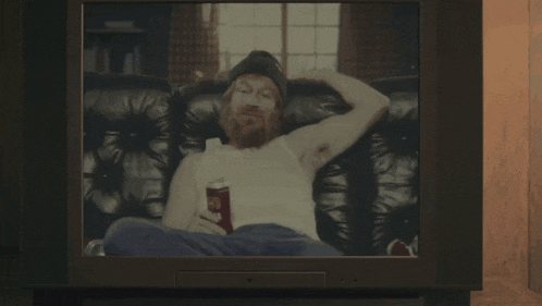 a tv screen shows a man sitting on a couch with a can of soda