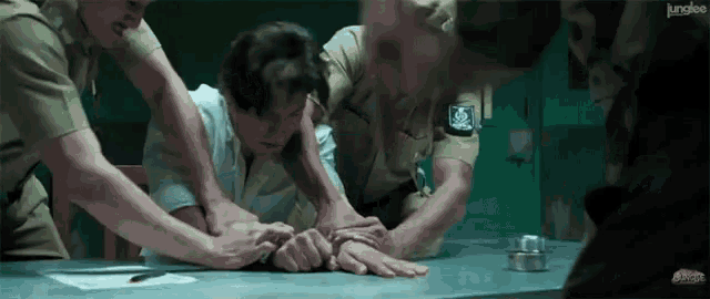a group of police officers are holding a man in a room with junglee written on the bottom right corner