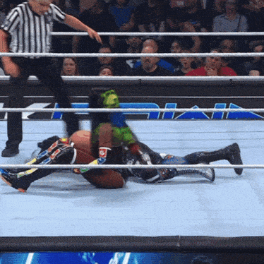 a wrestler with green hair is laying on the ground