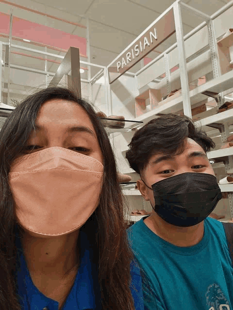 a man and a woman wearing face masks in front of a sign that says parisian