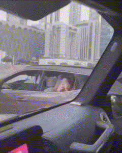 a person is sitting in the driver 's seat of a car with a city in the background .