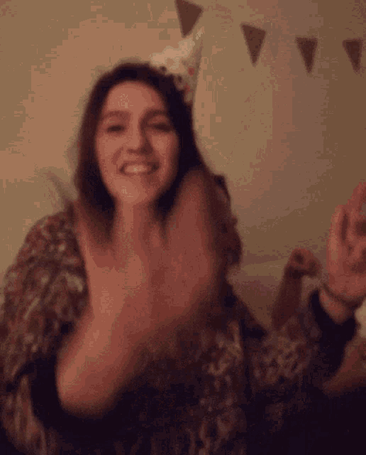 a woman wearing a party hat is dancing and smiling