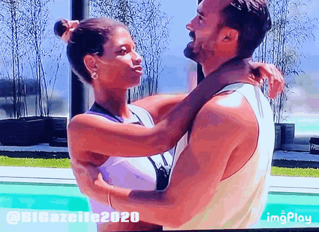 a man and a woman are hugging in front of a pool with a watermark that says imgplay on it