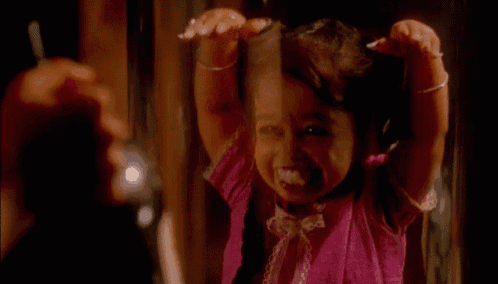 a little girl is looking at herself in a mirror and smiling .