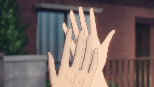 two hands are reaching out towards each other in front of a brick building