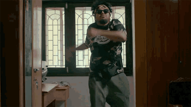 a man wearing sunglasses and a dickies shirt is dancing