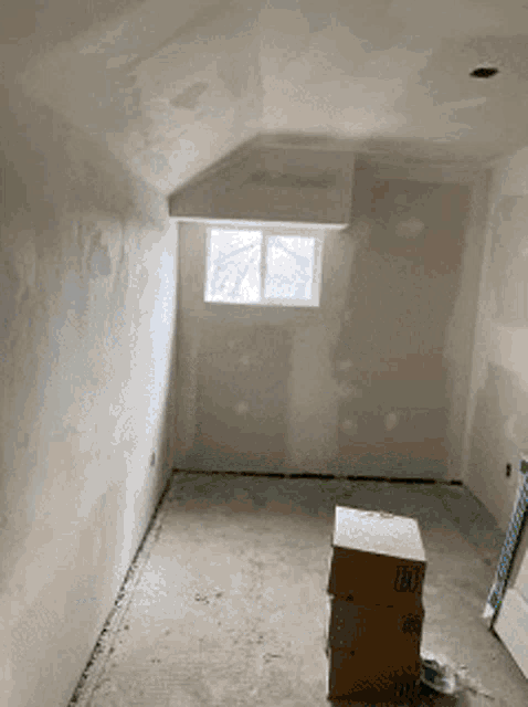 a room with a window and cardboard boxes on the floor .