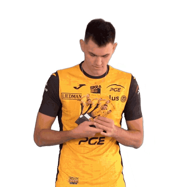 a man wearing a yellow pge shirt holds a piece of paper in his hand