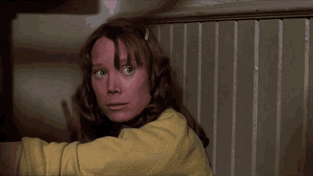 a woman in a yellow jacket has a clip in her hair that says ' a ' on it