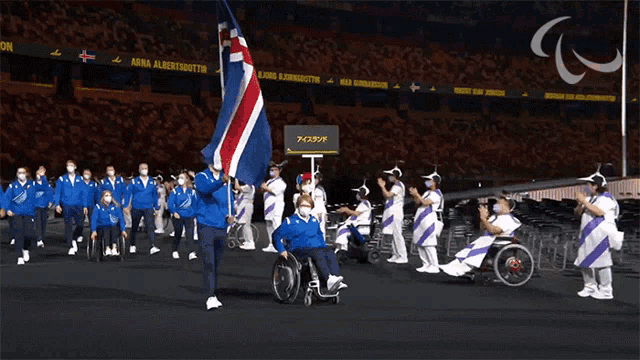 a person in a wheelchair is holding a flag in front of a sign that says arna albertsdottir