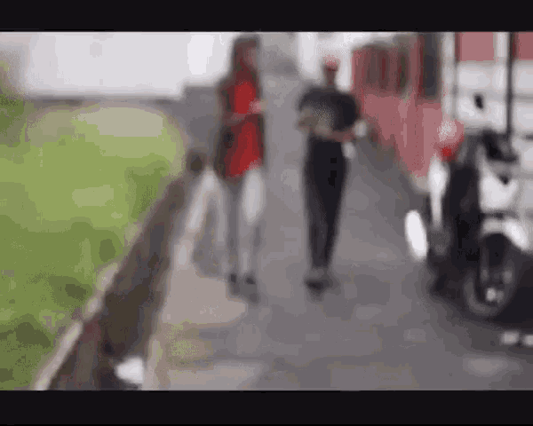 a blurry picture of a man and a woman walking down a sidewalk .