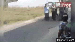 a group of people are standing on the side of a road in a field .
