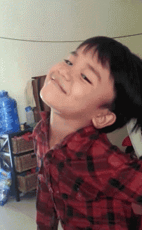 a young boy wearing a red plaid shirt looks up at the sky