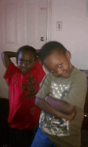 two young boys posing for a picture one of whom is wearing a red shirt with a fleur de lis design on it