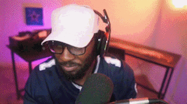 a man with a beard wearing headphones and a hat is sitting in front of a microphone .