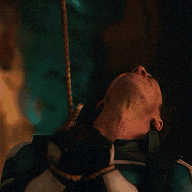 a man is holding a rope around his neck and making a face