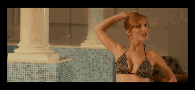 a woman in a bikini is standing in front of a pool