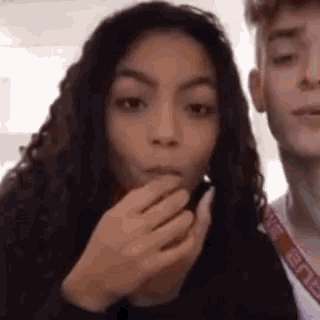 a man and a woman are standing next to each other . the woman is eating something from the man 's hand .