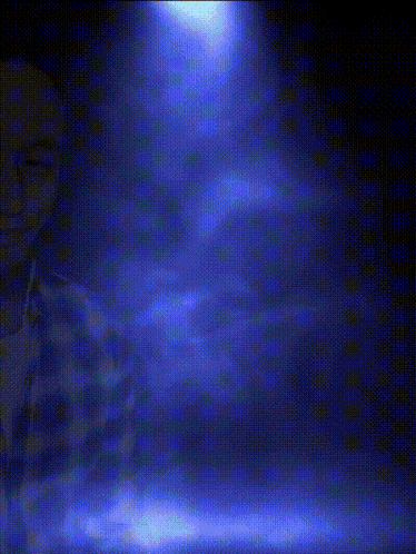a man wearing headphones and a plaid shirt looks at the camera