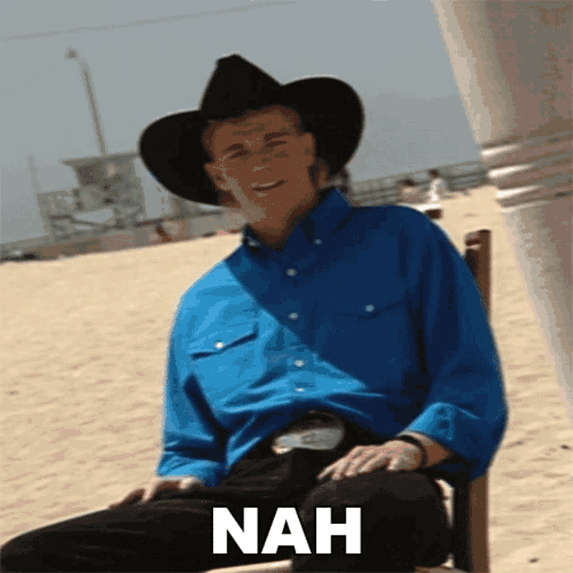 a man wearing a cowboy hat is sitting on a chair with the word nah written below him