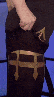 a person is taking off a black shirt with a gold belt .