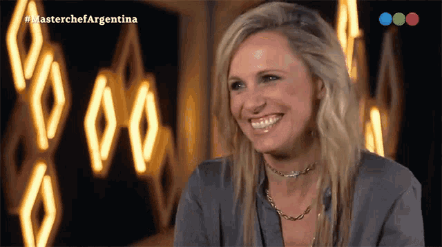 a woman is smiling in front of a sign that says masterchefargentina
