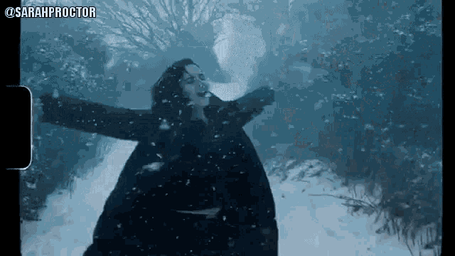 a woman is standing in the snow with her arms outstretched