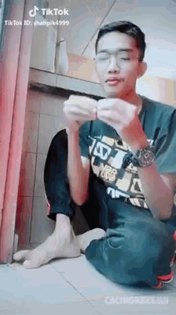 a young man is sitting on the floor holding a piece of paper .