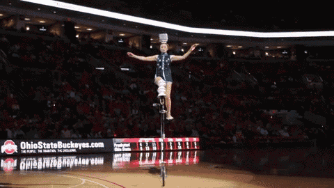 a person on a unicycle in front of a sign that says ohio state buckeyes.com